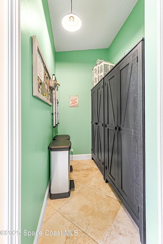 laundry area featuring light tile patterned floors, a textured ceiling, and baseboards