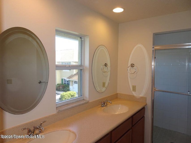 full bathroom with double vanity, recessed lighting, a sink, and a shower stall