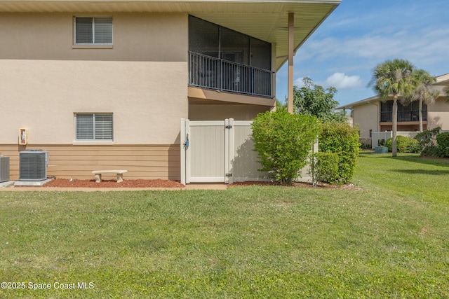 back of property featuring stucco siding, a yard, fence, and central AC unit