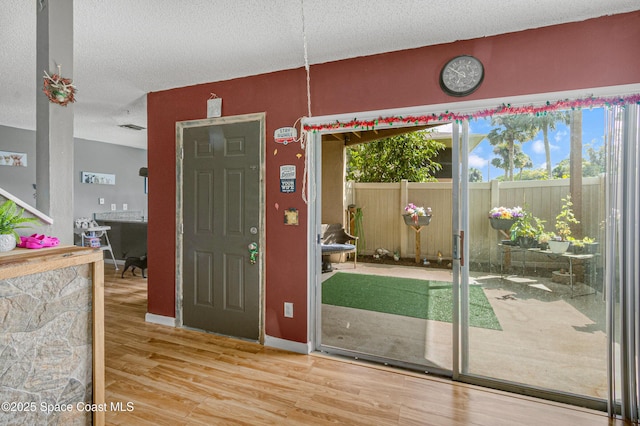 entrance foyer with a textured ceiling, baseboards, and wood finished floors