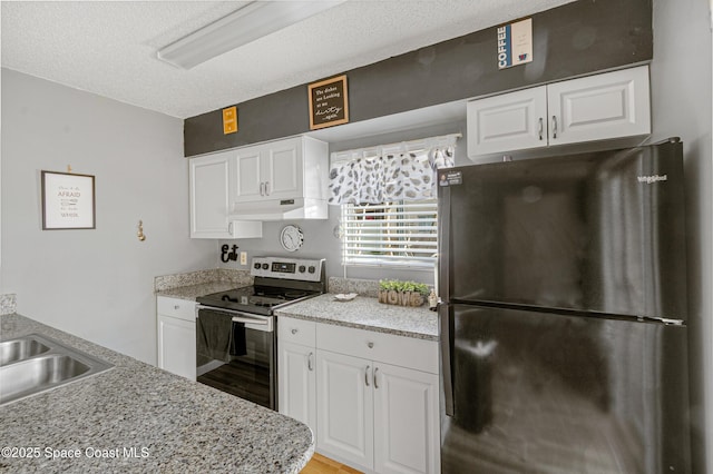 kitchen featuring freestanding refrigerator, white cabinets, a textured ceiling, under cabinet range hood, and stainless steel electric range