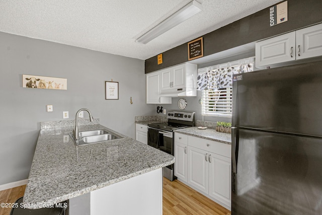 kitchen with a peninsula, a sink, freestanding refrigerator, stainless steel electric range oven, and light wood finished floors