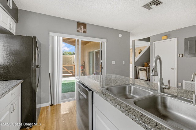 kitchen with light wood finished floors, visible vents, appliances with stainless steel finishes, white cabinetry, and a sink