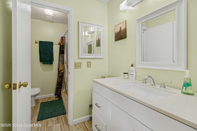 bathroom with baseboards, a shower with shower curtain, toilet, wood finished floors, and vanity