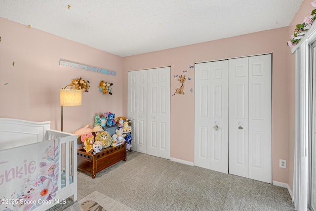 bedroom featuring multiple closets, carpet, a textured ceiling, and baseboards