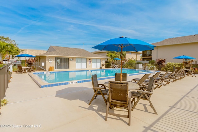 community pool with fence, outdoor dining area, and a patio