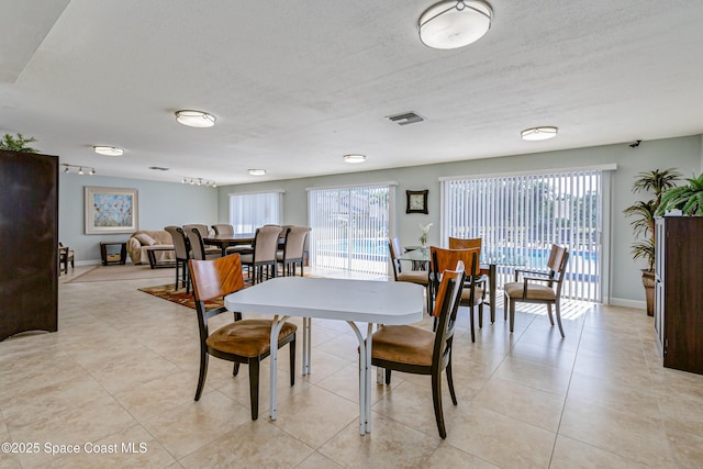 dining area featuring baseboards, a textured ceiling, visible vents, and a wealth of natural light