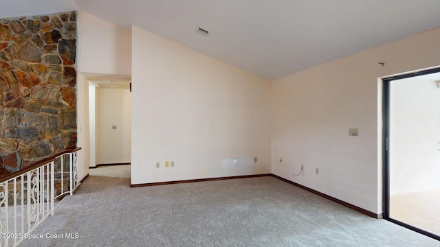 spare room featuring carpet floors, baseboards, visible vents, and vaulted ceiling