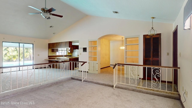 empty room featuring light carpet, visible vents, arched walkways, high vaulted ceiling, and a sink