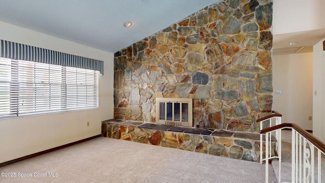 unfurnished living room featuring vaulted ceiling, carpet floors, a stone fireplace, and baseboards