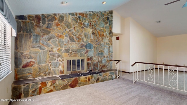 interior space featuring carpet floors, a fireplace, vaulted ceiling, and visible vents