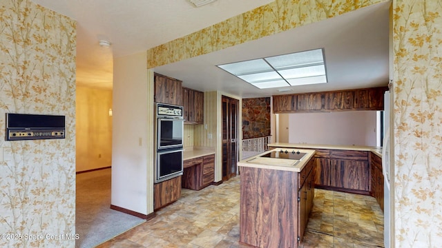 kitchen featuring double oven, light countertops, a center island, stone finish flooring, and wallpapered walls