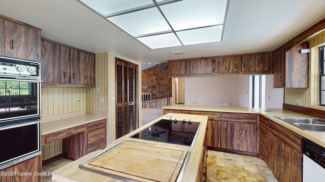 kitchen featuring black appliances, stone finish floor, light countertops, and a sink