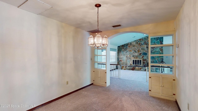 unfurnished dining area with a fireplace, visible vents, an inviting chandelier, carpet flooring, and baseboards