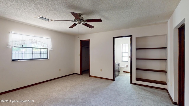 unfurnished bedroom featuring visible vents, carpet flooring, connected bathroom, a textured ceiling, and baseboards