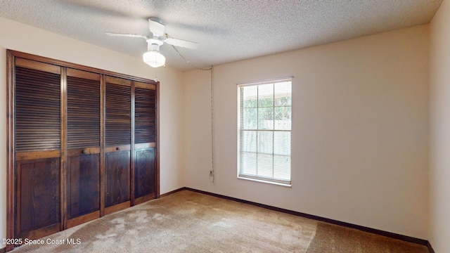 unfurnished bedroom featuring light carpet, baseboards, ceiling fan, a textured ceiling, and a closet