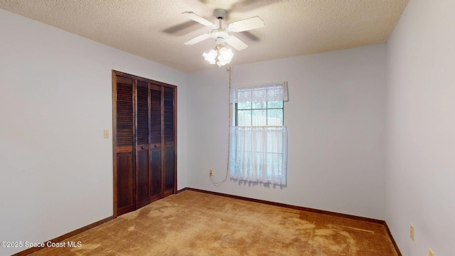 spare room featuring a ceiling fan, light carpet, a textured ceiling, and baseboards