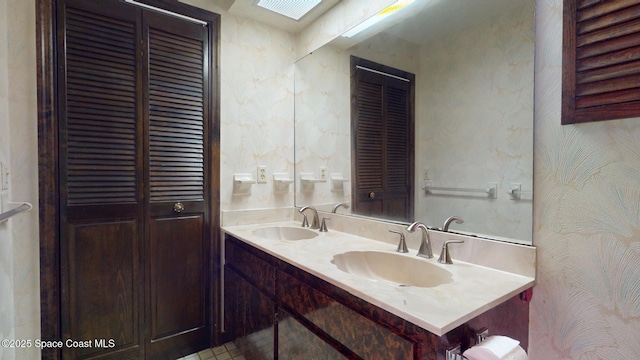 bathroom with a closet, a sink, and double vanity