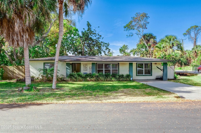 ranch-style house featuring a front yard, concrete driveway, fence, and stucco siding