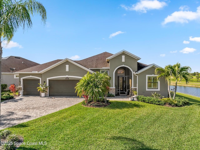 mediterranean / spanish-style house with a front lawn, decorative driveway, a garage, and stucco siding