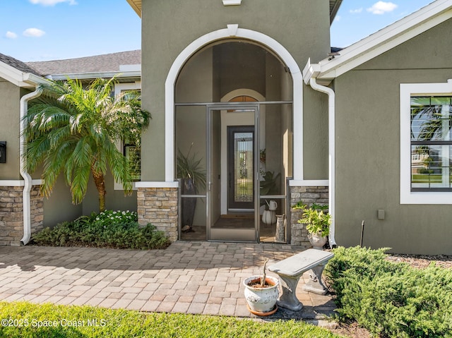 doorway to property with stucco siding and stone siding