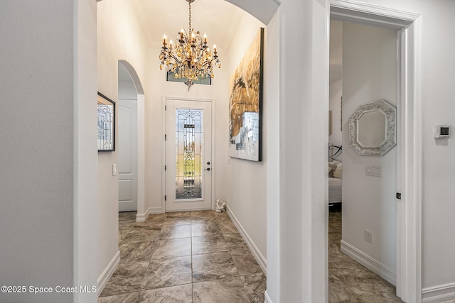 entryway with an inviting chandelier, baseboards, and arched walkways