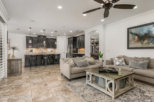 living area with recessed lighting, arched walkways, ceiling fan, and crown molding