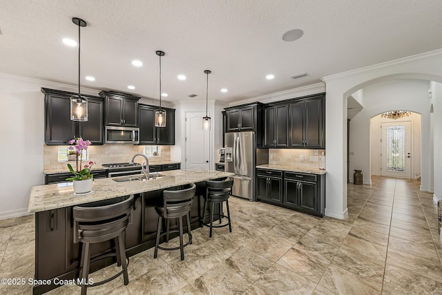 kitchen featuring light stone counters, visible vents, arched walkways, stainless steel appliances, and crown molding