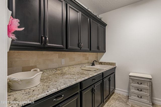 interior space with a textured ceiling, baseboards, and a sink