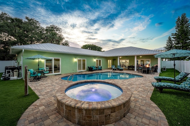 303 Harrison Ave, Cape Canaveral, FL 32920 - pool at dusk with a fenced in pool, a patio, an in ground hot tub, and fence