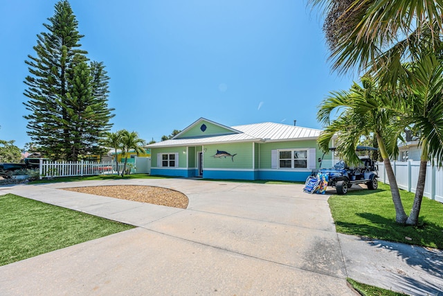 303 Harrison Ave, Cape Canaveral, FL 32920 - view of front of home with a front yard, fence, driveway, and metal roof