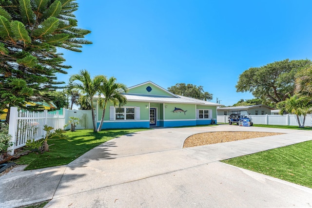 303 Harrison Ave, Cape Canaveral, FL 32920 - single story home with metal roof, concrete driveway, a front lawn, and fence