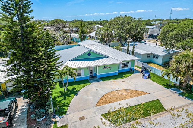 303 Harrison Ave, Cape Canaveral, FL 32920 - view of front of property featuring fence, a residential view, concrete driveway, a front yard, and metal roof