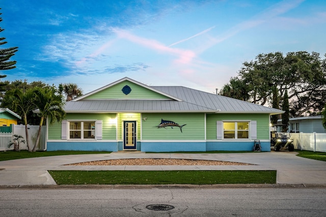 303 Harrison Ave, Cape Canaveral, FL 32920 - view of front facade featuring metal roof, concrete driveway, stucco siding, and fence