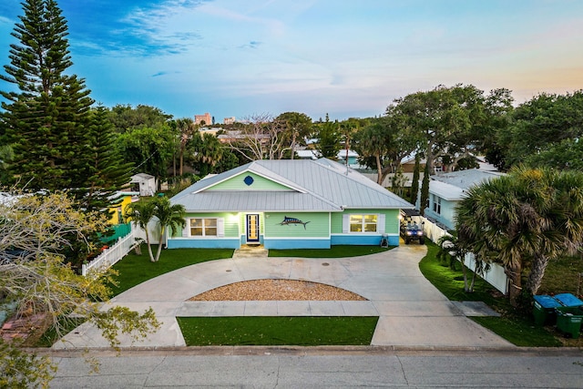 303 Harrison Ave, Cape Canaveral, FL 32920 - view of front of property with concrete driveway, fence, a front lawn, and metal roof
