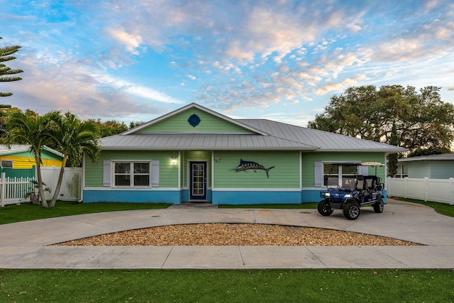 303 Harrison Ave, Cape Canaveral, FL 32920 - view of front of home with metal roof, a yard, concrete driveway, and fence