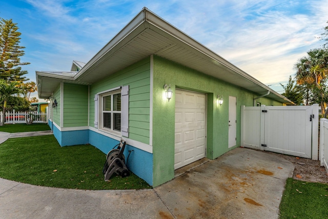303 Harrison Ave, Cape Canaveral, FL 32920 - view of property exterior with stucco siding, a gate, fence, a yard, and an attached garage