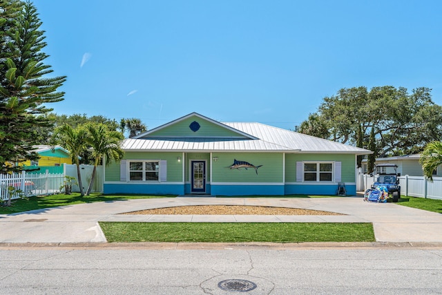 303 Harrison Ave, Cape Canaveral, FL 32920 - view of front facade with metal roof, concrete driveway, and fence