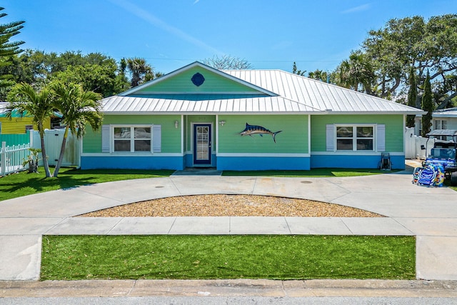 303 Harrison Ave, Cape Canaveral, FL 32920 - view of front facade featuring a standing seam roof, a front lawn, fence, and metal roof