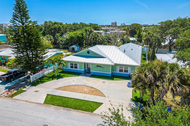 303 Harrison Ave, Cape Canaveral, FL 32920 - view of front of home featuring metal roof, concrete driveway, a front lawn, and fence