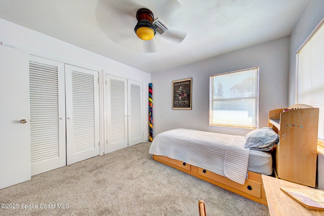 bedroom with carpet, ceiling fan, and two closets