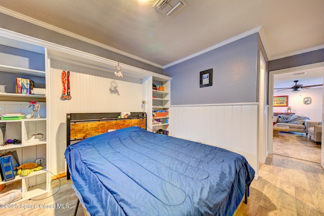 bedroom with visible vents, ornamental molding, wood finished floors, and wainscoting