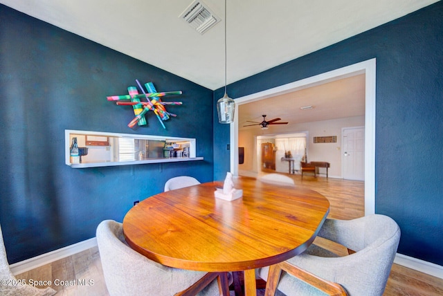 dining area featuring lofted ceiling, visible vents, ceiling fan, wood finished floors, and baseboards