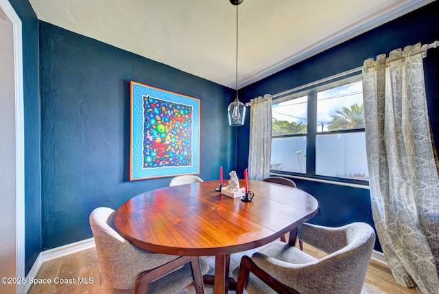 dining room with a textured wall, wood finished floors, and baseboards