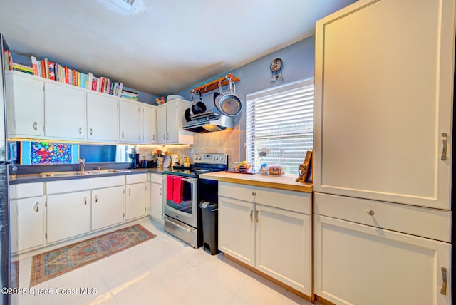 kitchen featuring tasteful backsplash, white cabinets, range hood, stainless steel electric stove, and a sink