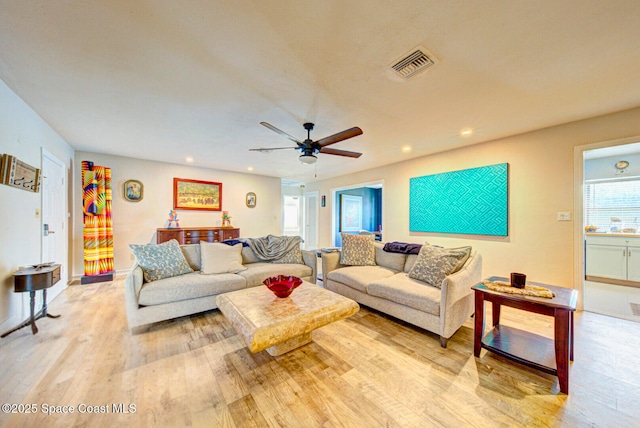 living room with light wood-type flooring, ceiling fan, visible vents, and recessed lighting