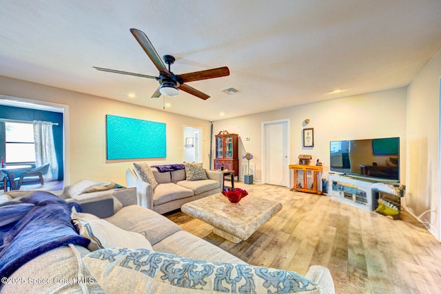 living room with ceiling fan, visible vents, and wood finished floors