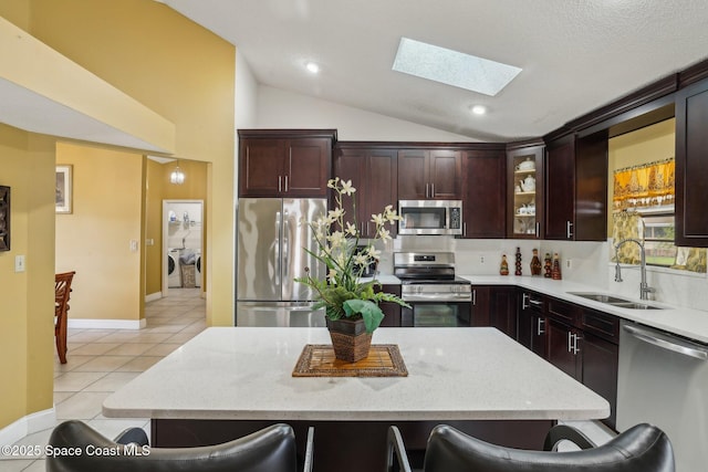 kitchen featuring lofted ceiling, stainless steel appliances, a kitchen bar, separate washer and dryer, and a sink