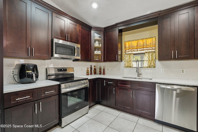 kitchen featuring light tile patterned flooring, stainless steel appliances, a sink, light countertops, and backsplash