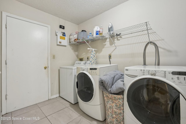 laundry room featuring a textured ceiling, laundry area, separate washer and dryer, and light tile patterned floors